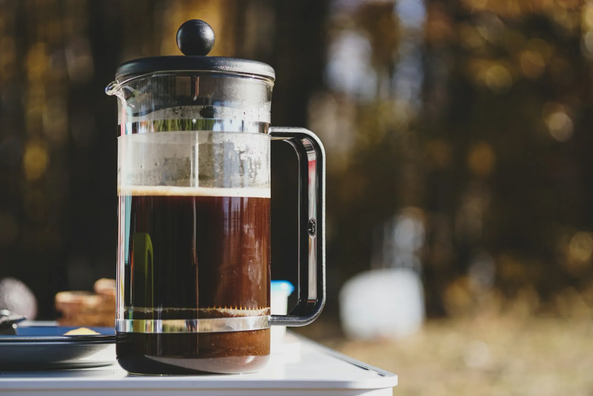 a french press with brewed coffee sitting on top of a table